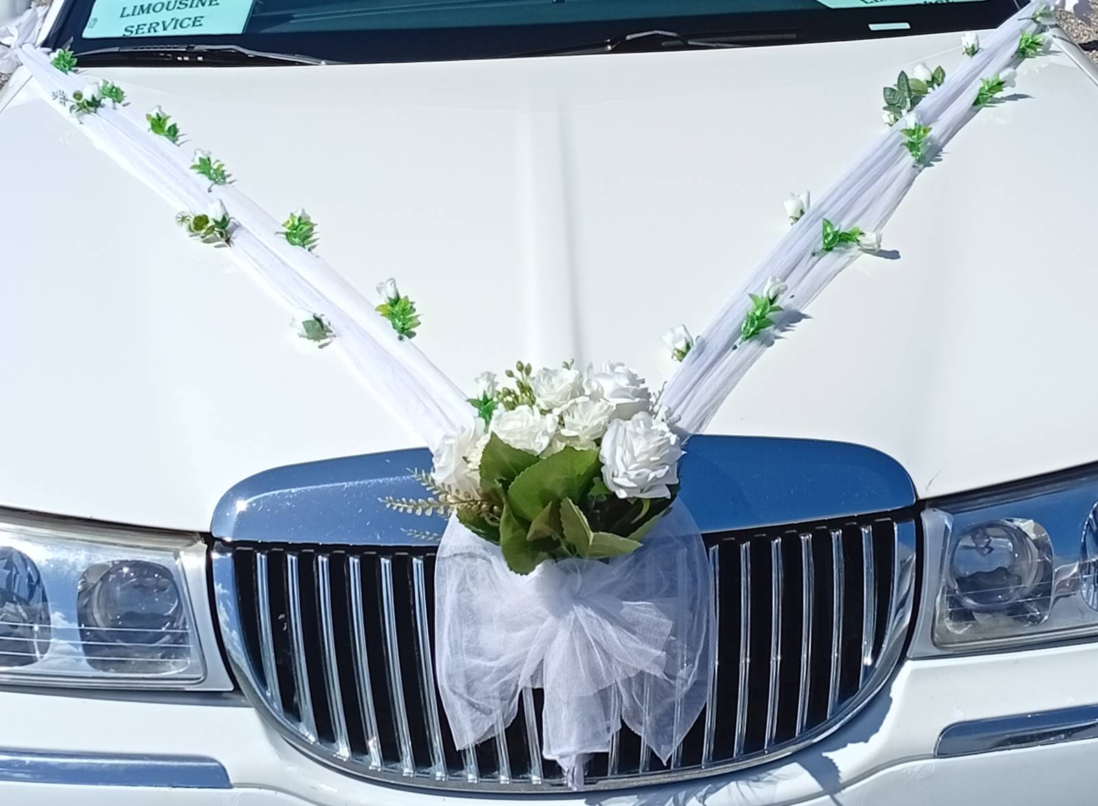 Hvid Lincoln-limousine pyntet med hvide roser og tyl til bryllup