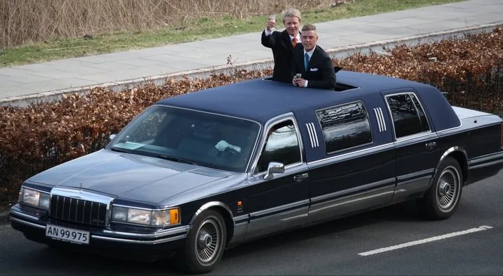 Den kongeblå Lincoln-limousine med gæster i soltaget