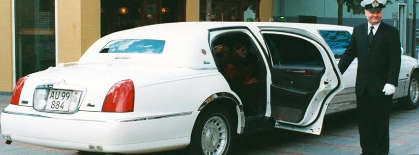 Den hvide Lincoln-limousine med chauffør i uniform ved den åbne dør